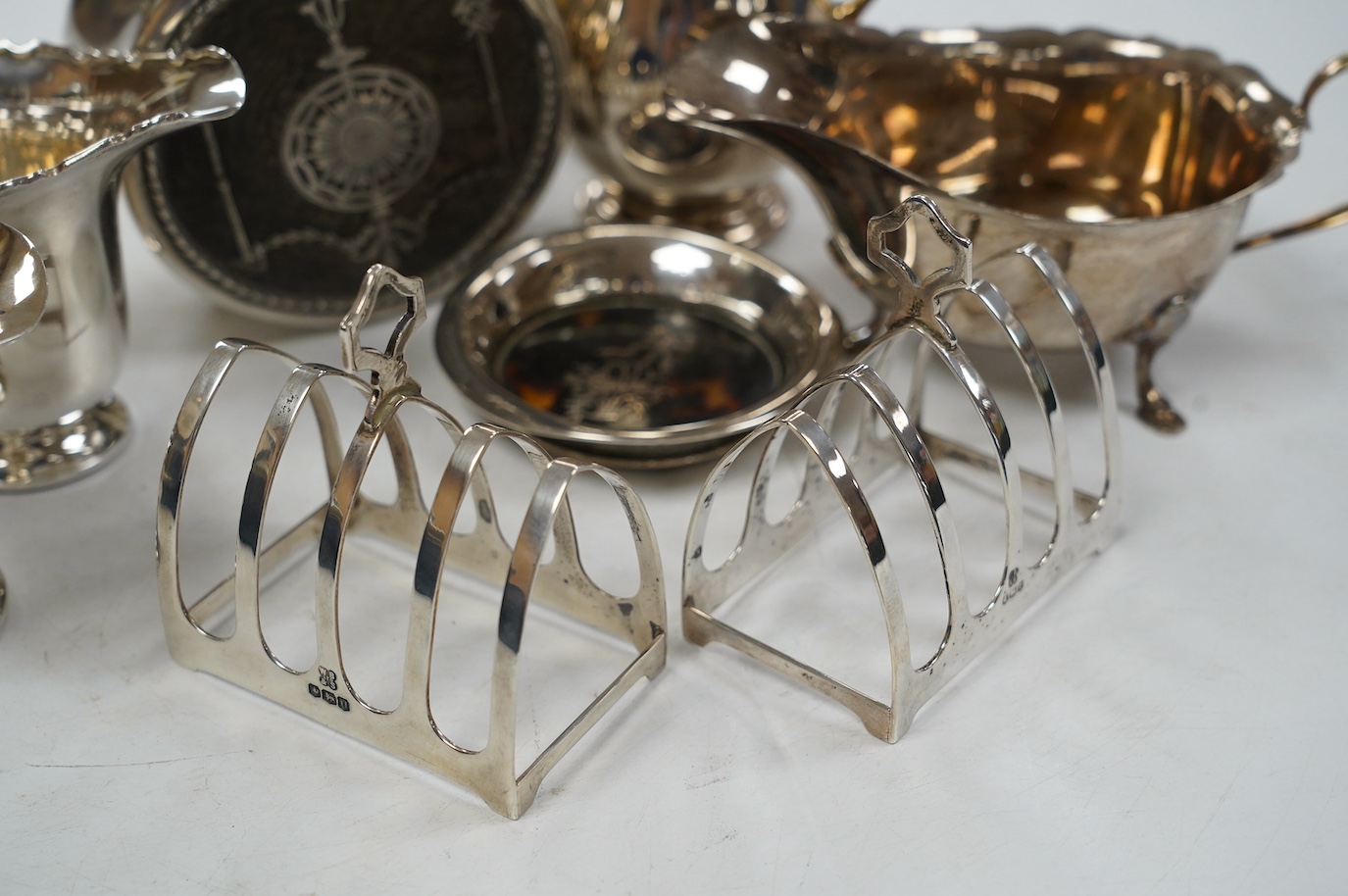 Sundry small silver including a pair of toast racks, Sheffield, 1936, three cream jugs, a sauceboat and two tortoiseshell mounted items. Condition - poor to fair to good